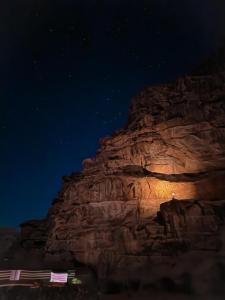 uma montanha rochosa à noite com estrelas no céu em Star City Camp wadirum em Wadi Rum