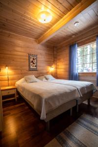 um quarto com uma cama grande num quarto de madeira em Lomavouti Cottages em Savonranta