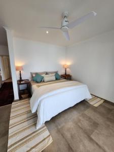 a white bedroom with a large white bed with blue pillows at Rocky Bay on the View in Gordonʼs Bay