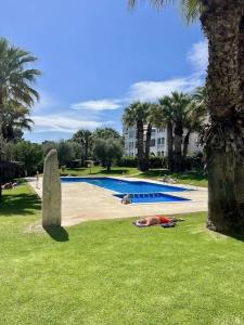 une personne allongée sur l'herbe à côté d'une piscine dans l'établissement Apartment VillaMartin Plaza - The Loft, à Orihuela Costa