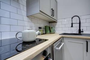 a white kitchen with a tea kettle on the stove at The Annick - Coorie Doon Apartments in Irvine