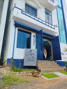un bâtiment bleu et blanc avec un panneau devant lui dans l'établissement Casa De Neel, à Pondichéry