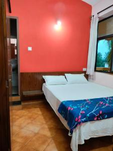 - une chambre dotée d'un lit avec un mur rouge dans l'établissement Villa Cleto Guest House, à Panaji
