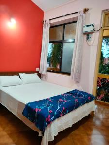 a bedroom with a bed with a red wall at Villa Cleto Guest House in Panaji