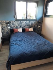 GITE DE LA PIERRE PLATE في لو تيلو: سرير مع لحاف أزرق في غرفة النوم
