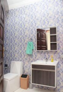 a bathroom with a sink and a toilet and a mirror at CNC Rehoboth Villa in Accra