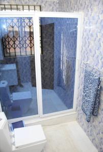 a bathroom with a toilet and a glass window at CNC Rehoboth Villa in Accra