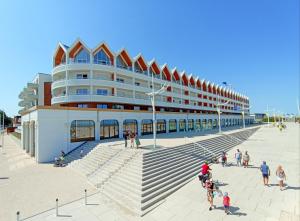 un grand bâtiment avec des personnes debout à l'extérieur dans l'établissement L'intemporel plage - Malo'Cation, à Dunkerque