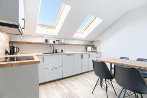 a kitchen with white cabinets and a wooden table at Azyl Widoki in Wielkie Leżno