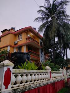 une maison jaune avec un palmier devant elle dans l'établissement Villa Cleto Guest House, à Panaji