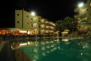 a swimming pool in front of a hotel at night at Sea Melody Beach Hotel Apartments in Ialysos