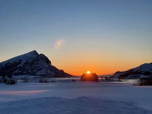 einen Sonnenuntergang über einem schneebedeckten Feld mit Sonnenuntergang hinter den Bergen in der Unterkunft Koselig hus i landlig område in Bolle