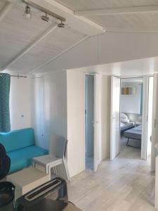 Mobil Home Comfort XL 6 Personnes Montalivet في فيندايز - مونتاليفت: غرفة معيشة مع أريكة زرقاء وغرفة نوم
