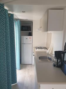 Il comprend une petite cuisine équipée d'un évier et d'une cuisinière. dans l'établissement Mobil Home Comfort XL 6 Personnes Montalivet, à Vendays-Montalivet