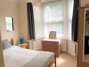a bedroom with a bed and a dresser and windows at Spacious West London 2 Bedroom Apartment in London