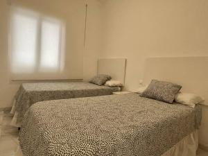 Duas camas num quarto branco com uma janela em Apartamento La Victoria em Córdoba