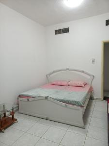 een wit bed in een witte kamer met roze kussens bij Holiday Home 2 Bedrooms Apartment for Family Only in Sharjah