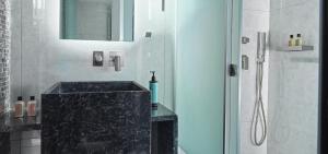 y baño con lavabo negro y ducha. en Nautilux Rethymno by Mage Hotels, en Rethymno