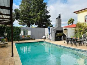 a swimming pool in front of a house with a fireplace at Welgemoed Villa in Bellville