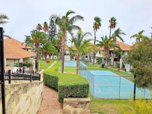 a house with a tennis court and palm trees at Carras Loft Villa Near the Sea Sleeps 5 in Mandurah