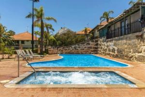 a swimming pool in a patio with chairs and a building at Carras Loft Villa Near the Sea Sleeps 5 in Mandurah