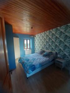 a bedroom with a bed and a wooden ceiling at La Parent'aise un brin d'Auvergne 