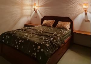 a bed in a bedroom with two lights on the wall at Sarang Walet Homestay in Tetebatu