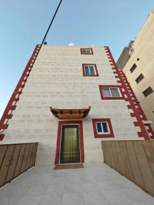 un edificio alto de ladrillo blanco con acentos rojos en iHome Petra en Wadi Musa
