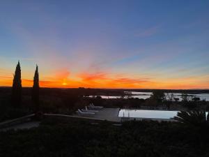 a sunset over a swimming pool with the sun setting at Herdade Do Charito in Elvas