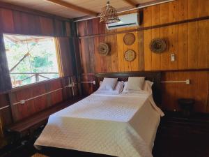 ein Schlafzimmer mit einem Bett in einem Holzzimmer in der Unterkunft Ponta Poranga Jungle Lodge in Manaus
