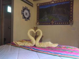 dois cisnes de toalha sentados em cima de uma cama em Salkantay Hostel Chaullay em Santa Teresa