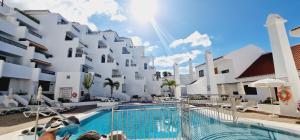 a hotel with a swimming pool in front of a building at Garajonay 3 bedrooms apartment, ocean & pool view in Playa Fañabe