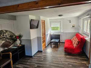 LA BOURZEDE في Langeac: غرفة معيشة مع أريكة حمراء وتلفزيون