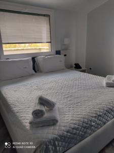 un letto bianco con un asciugamano sopra e una finestra di Hotel Calypso a Pontecagnano