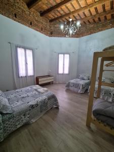 a bedroom with two beds and a chandelier at Lechuza Alvear in San Antonio de Areco
