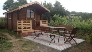 une table de pique-nique et des bancs devant une petite cabine dans l'établissement Vinný sklípek U Nováků, à Vrbovec