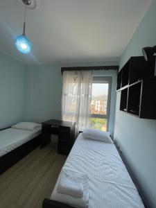 a small bedroom with two beds and a window at Sunny Apartment near Castle in Elbasan