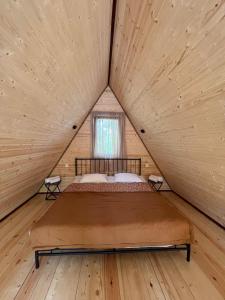 Cama en habitación de madera con ventana en Agaruka Cabin Racha, en Ambrolauri