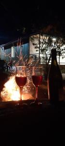 two glasses of wine and a bottle in front of a fire at BANI tsikhisdziri in Tsikhisdziri