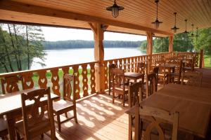 a wooden deck with tables and chairs and a view of a lake at Folwark Hutta in Suwałki