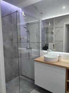 a bathroom with a glass shower and a sink at Apartament Przystań z tarasem in Giżycko