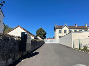 an empty street in front of a house with a fence at Le porte plume in Dole