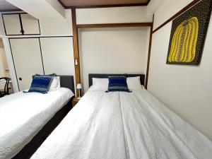 Duas camas num quarto com lençóis brancos e almofadas azuis em Nearest ASAKUSA station have Elevator Ginza 17min Ueno 5min Shibuya 34min omotesanto 30min em Tóquio