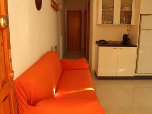 an orange couch in a room with a kitchen at La casetta di Torre dell'Orso in Torre dell'Orso +3 photos