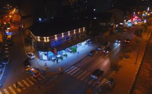 una calle de la ciudad por la noche con coches aparcados frente a un edificio en Prenoćište-Sobe My Place en Novi Pazar