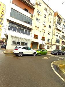 ein weißes Auto, das vor einem Gebäude parkt in der Unterkunft Piazza_Apartments_Tirana in Tirana