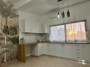 a kitchen with white cabinets and a large window at Victorias apartment Tirane in Tirana
