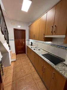a large kitchen with wooden cabinets and a sink at Casa Cuevas del Sol in Setenil