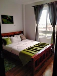 1 cama grande en un dormitorio con ventana en Two Bedrooms Furnished Apartment in Nakuru en Nakuru