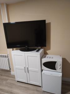 a tv on top of a white cabinet with a microwave at Un Rincón Tranquilo. in Manzanares el Real